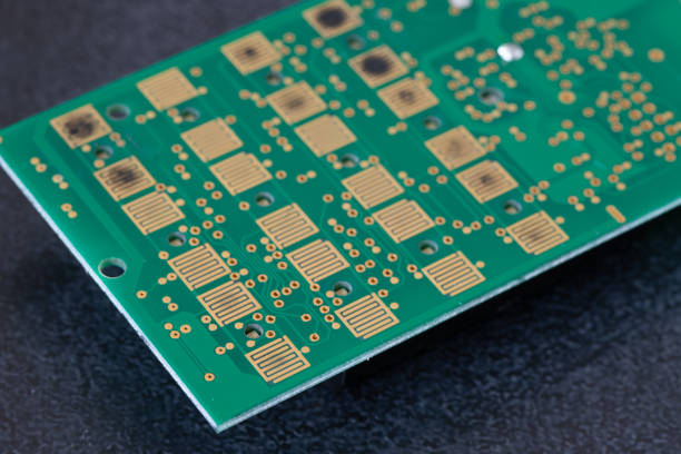 Close view of exposed PCB pads on a green solder-mask board; the exact finish chemistry is not visually distinguishable