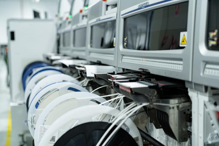 Surface-mount component reels staged at automated pick-and-place feeders on an electronics assembly line
